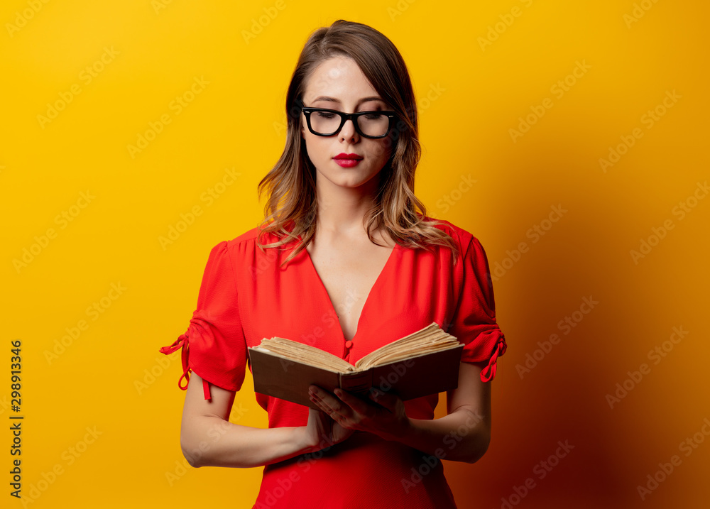 Beautiful woman in red dress with book on yellow background Beautiful woman in red dress with book on yellow background