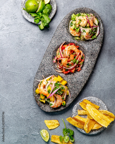 CEVICHE. Three colorful shrimps ceviche with mango, avocado and tomatoes. Latin American Mexican Peruvian Ecuadorian food. Served with white wine and banana chips photo