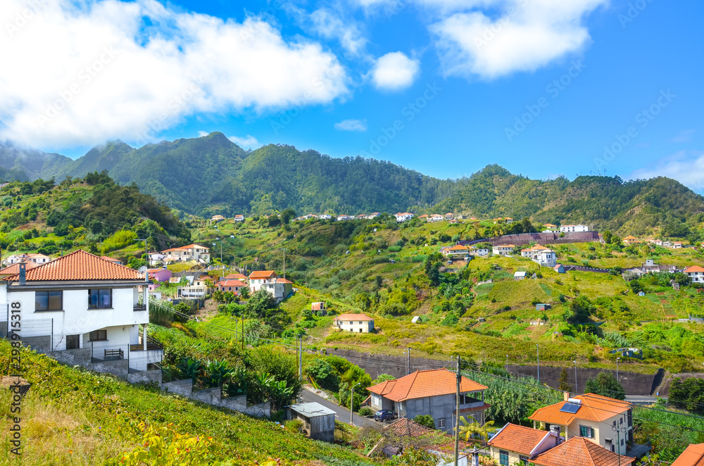 Beautiful village Porto da Cruz in Madeira island, Portugal. A small city surrounded by green hills and forest. Rural buildings on a hill. Remote area, Portuguese landscapes. Tourist destination