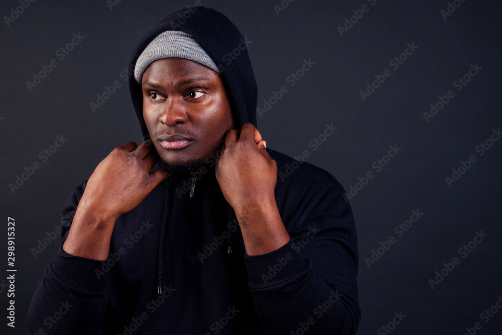 handsome afro-america male wearing gray hat and black hoody with hood serious and strong look at the camera studio shot background handsome afro-america male wearing gray hat and black hoody with hood serious and strong look at the camera studio shot background