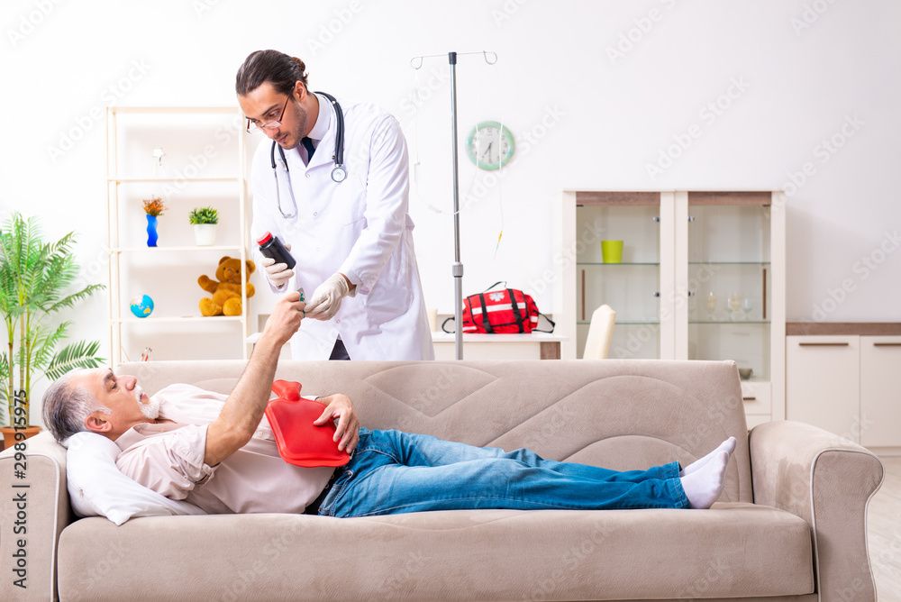 Obraz premium Young male doctor visiting old patient at home