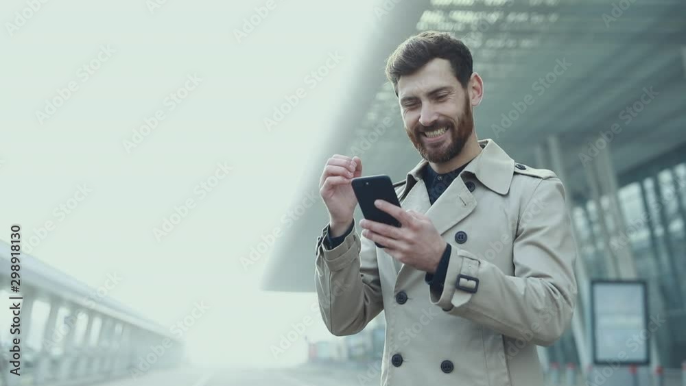 Success and achievement - happy businessman cheering celebrating looking at cell phone. Young urban professional successful business man receiving good news in business. Smartphone app concept Success and achievement - happy businessman cheering celebrating looking at cell phone. Young urban professional successful business man receiving good news in business. Smartphone app concept