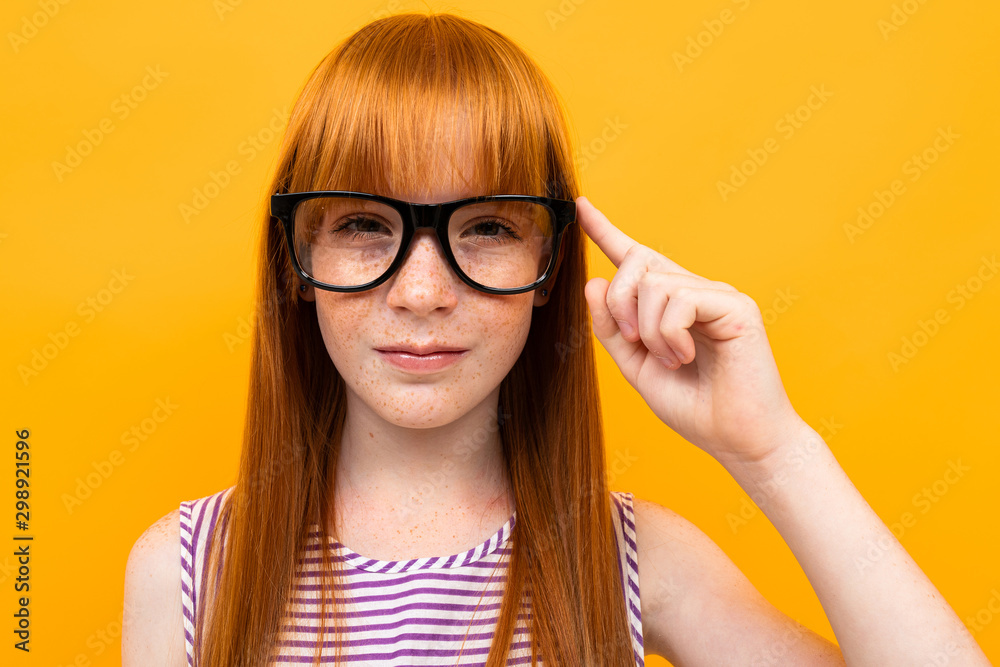 red-haired teenager in the background of an orange wall with glasses for vision red-haired teenager in the background of an orange wall with glasses for vision