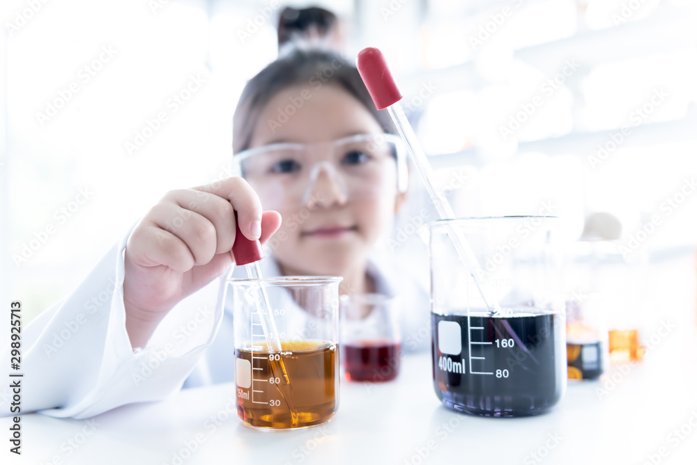 Blur images of A 6 year old Asian girl wearing a white scientist uniform Learning And conducted a scientific experiment on a white table with a measuring cup and test tube placed, to education concept Blur images of A 6 year old Asian girl wearing a white scientist uniform Learning And conducted a scientific experiment on a white table with a measuring cup and test tube placed, to education concept