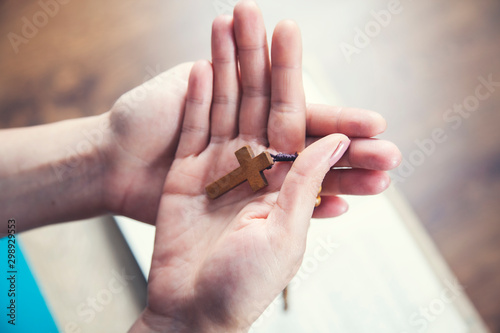 woman hand wooden cross on book