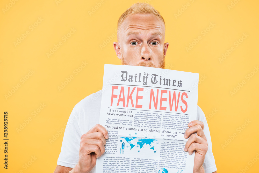 surprised bearded man holding newspaper with fake news, isolated on yellow surprised bearded man holding newspaper with fake news, isolated on yellow