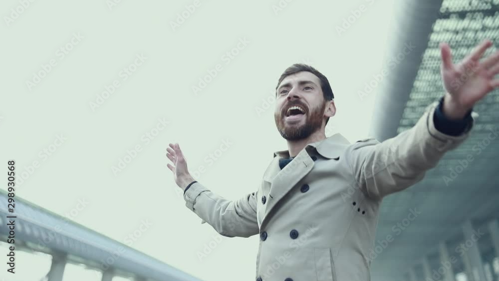 Cheerful and Happy Businessman is Actively Dancing on a Street Next to an Urban Concrete Wall. He's Wearing a Grey Suit. Sunny Day. Cheerful and Happy Businessman is Actively Dancing on a Street Next to an Urban Concrete Wall. He's Wearing a Grey Suit. Sunny Day.