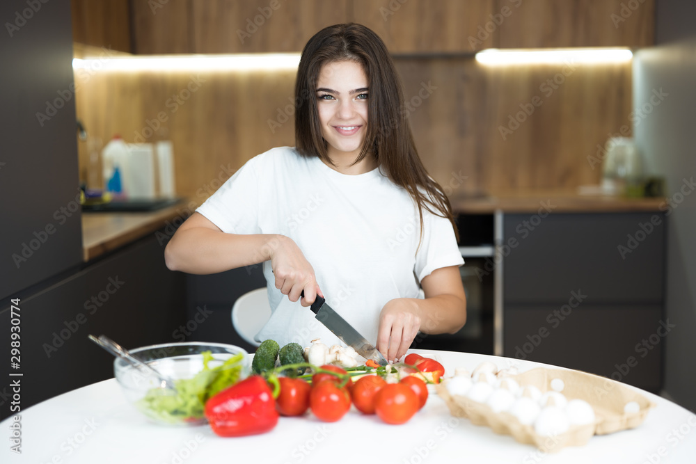 young beautiful smiling woman chopping tomatoes cooking breakfast in the kitchen looking happy