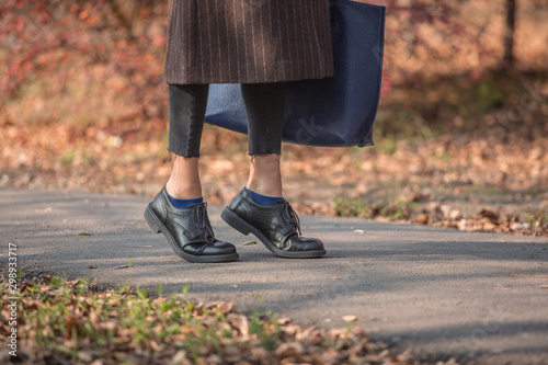Closeup legs fashionable woman wear black shoes and brown coat. Stylish fall outfit