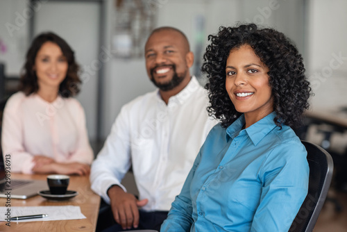 Diverse businesspeople smiling while sitting together at an office table