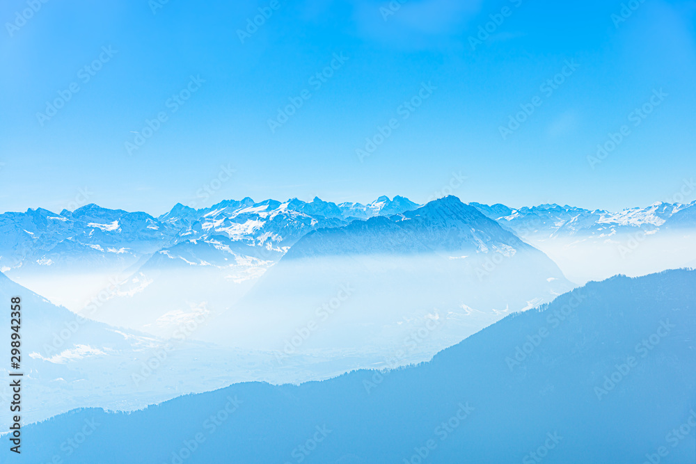 Majestic unique misty blue alpine skyline aerial view panorama of iced Swiss Alps and blue sky, taken from inside a cable lift cabin at mount Rigi Switzerland.