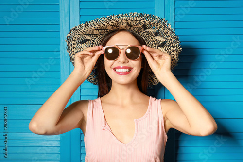 Slika na platnu Beautiful woman wearing sunglasses and hat near blue wooden folding screen