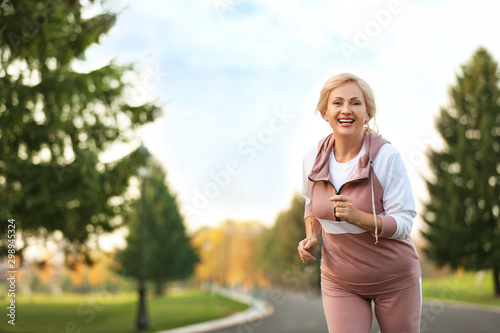 Fototapeta Naklejka Na Ścianę i Meble -  Mature woman jogging in park. Active lifestyle