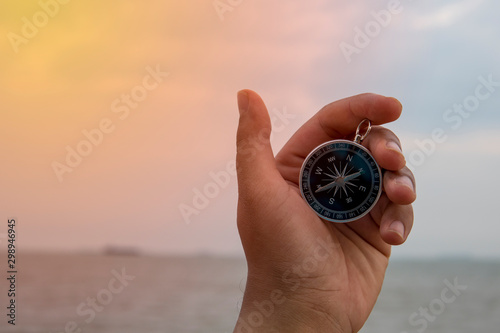 Hand holding compass with seaview blur focus, Tracking and survival concept.
