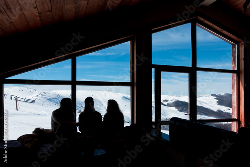 The silhouettes of three young ladies in the cosy atmosphere in the chalet of 3-5 Pigadia ski center