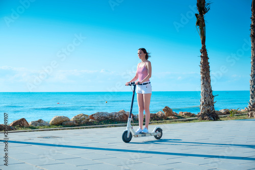 Young woman with electric scooter on a sea coast photo