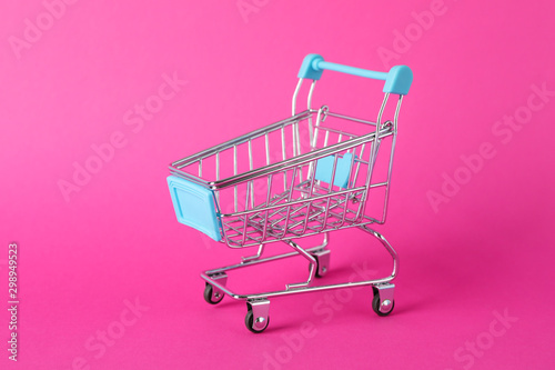Small shopping cart on pink background, space for text