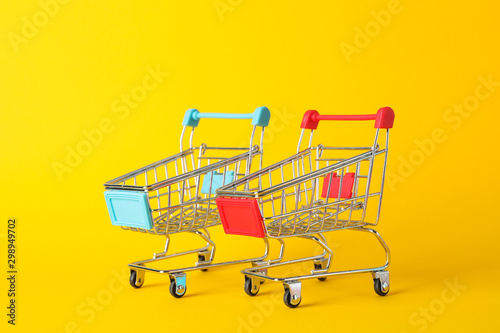 Small shopping carts on yellow background, space for text