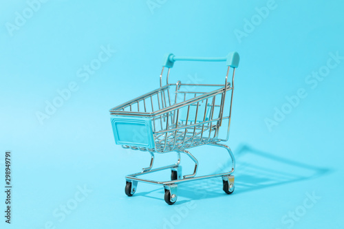 Small shopping cart on blue background, space for text