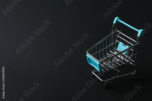 Small shopping cart on black background, space for text