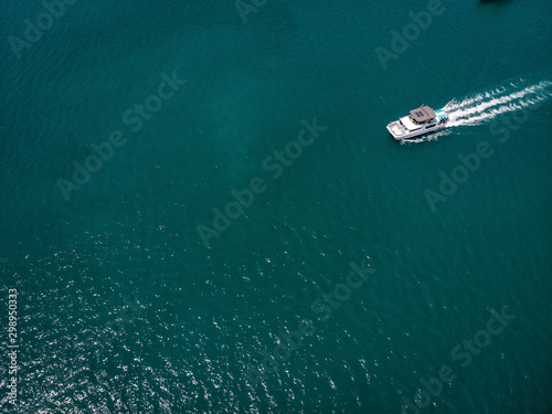 Bird eye view of the white motor boat moving fast, the vessel leaves a beautiful white trace behind  boating concept. © Semachkovsky 