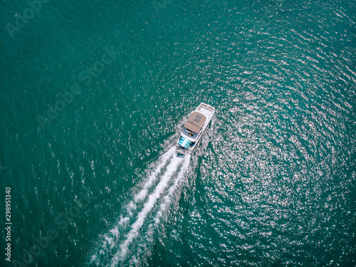 Bird eye view of the white motor boat moving fast, the vessel leaves a beautiful white trace behind  boating concept. © Semachkovsky 