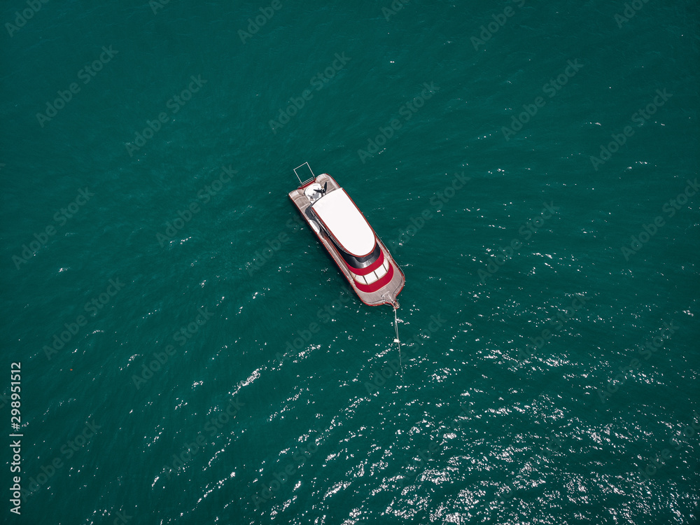 Drone view of the small brand-new red and white motorboat in blue sea, it shines in the bright sun; vessels concept. Drone view of the small brand-new red and white motorboat in blue sea, it shines in the bright sun; vessels concept.