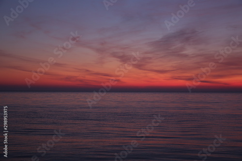 Beautiful red sunset on the sea. Bright colors of sunset are reflected in the water.