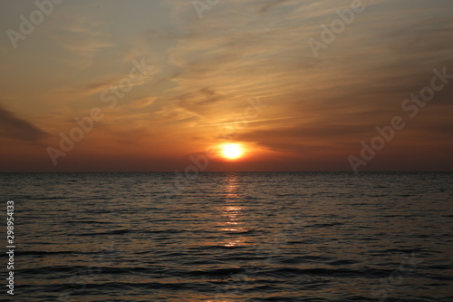 Beautiful bright sunset over the sea with reflection in the water. © Irina Tarzian
