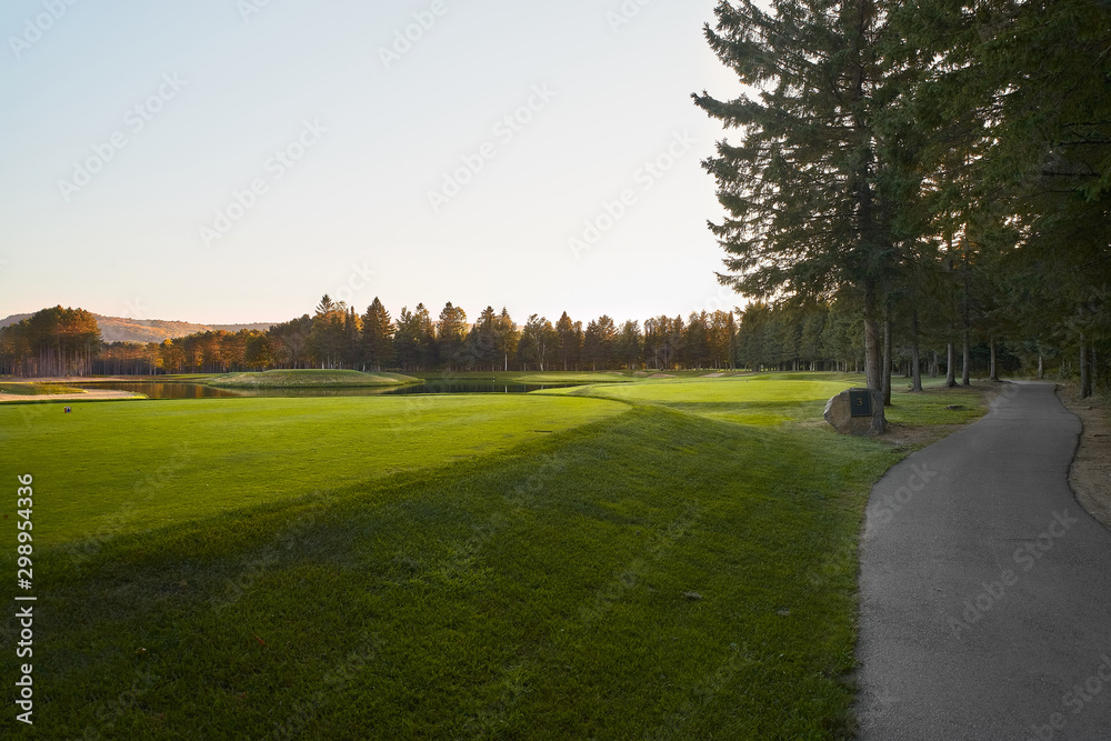 Obraz premium Sunset at the Golf Course - The sun sets on a putting green at the golf course in Autumn