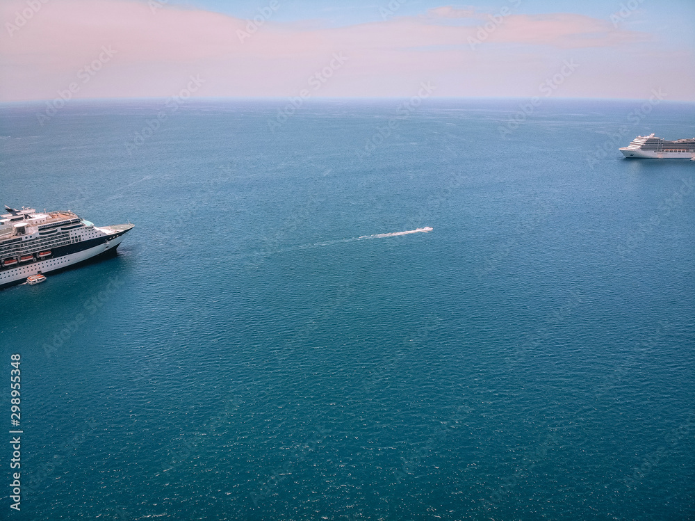 Drone shot of the snout of the cruise ships in a voyage by sea, boats nearby; horizon, vast blue waters.