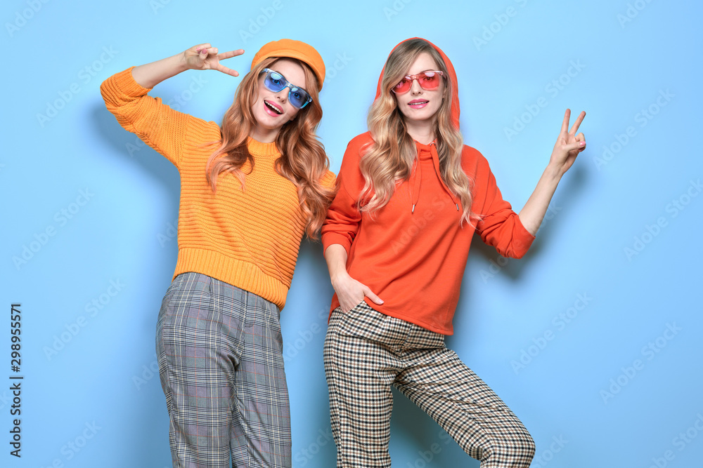 Two easy-going happy hipster Woman smiling in Stylish fashion orange colored outfit. Beautiful Girl in Trendy sweatshirt, cap. Joyful sister, friend, Creative fashionable friendship concept Two easy-going happy hipster Woman smiling in Stylish fashion orange colored outfit. Beautiful Girl in Trendy sweatshirt, cap. Joyful sister, friend, Creative fashionable friendship concept