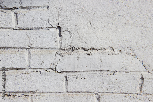 Texture of a brick wall coated with white paint and partially covered with plasterwork