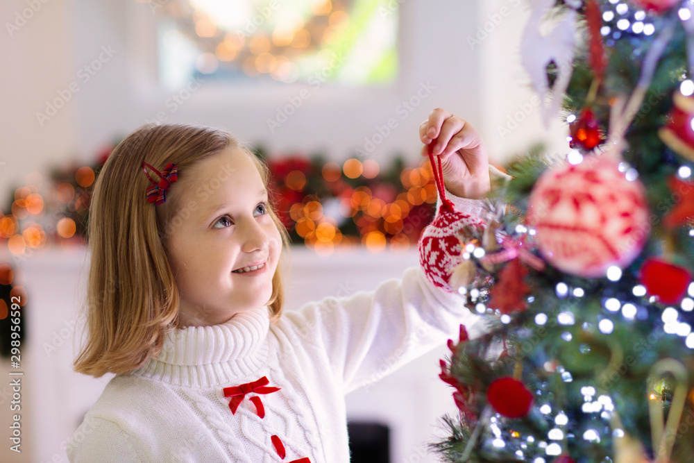 Child decorating Christmas tree. Kid on Xmas eve.