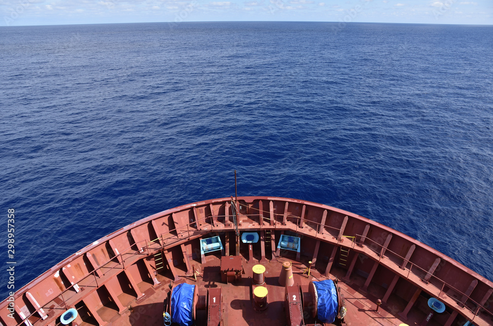 Cargo ship sailing through the calm ocean, view on the forward mooring stations. 