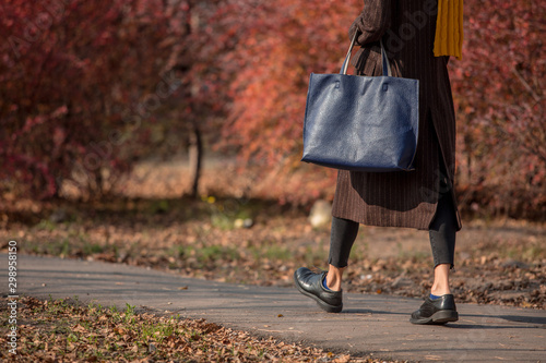 Fashionable autumn woman in trendy fall outfit walking in autumn park