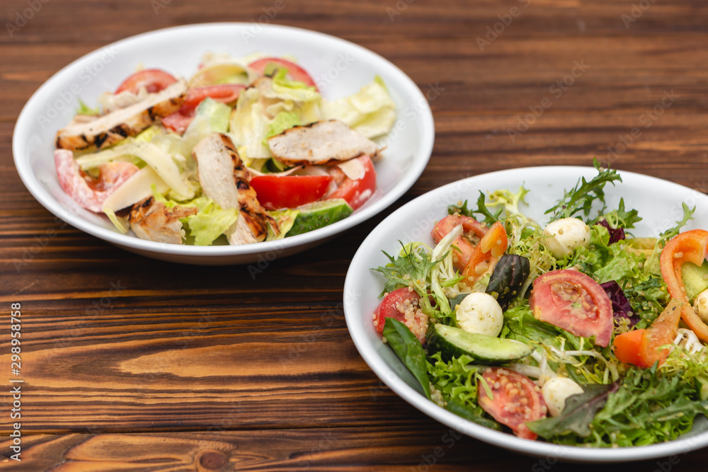 white deep plates with fresh salad ingredients mixed with sauce placed on an attractive background. A place for a menu, banner or advertisement white deep plates with fresh salad ingredients mixed with sauce placed on an attractive background. A place for a menu, banner or advertisement