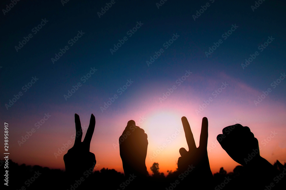 Silhouette of hands gesture V (victory) sign and fist power for victory or peace at sunset. Concept: success and winner in 2020. Silhouette of hands gesture V (victory) sign and fist power for victory or peace at sunset. Concept: success and winner in 2020.