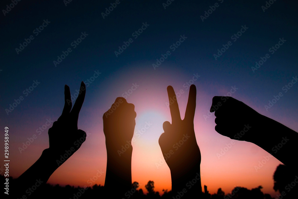 Silhouette of hands gesture V (victory) sign and fist power for victory or peace at sunset. Concept: success and winner in 2020.