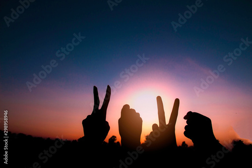 Silhouette of hands gesture V (victory) sign and fist power for victory or peace at sunset. Concept: success and winner in 2020.