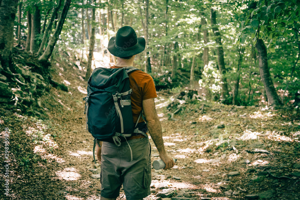 Hiker with black hat walking through a mediterranean forest