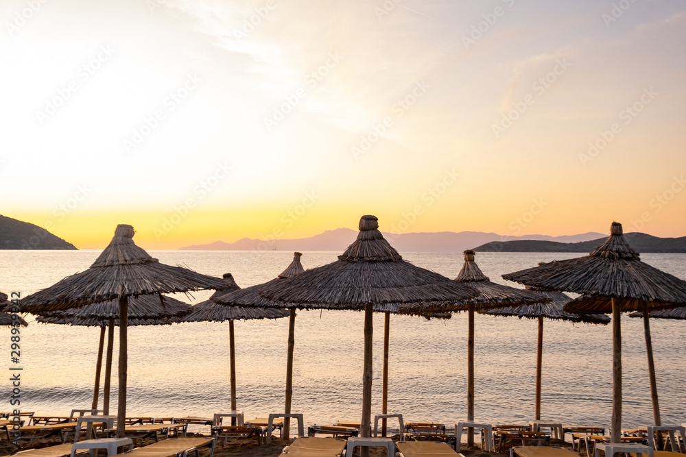 Beach umbrella in the Greece, landscape with beautiful sunrise and summer beach