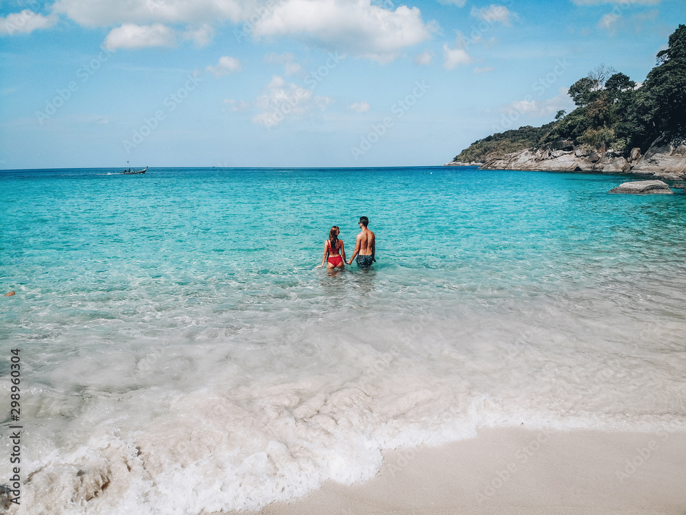 Happy loving couple standing in the blue water near the sandy beach; honeymoon concept. Happy loving couple standing in the blue water near the sandy beach; honeymoon concept.