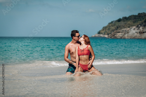 Loving couple sitting on the wet sand near the ocean kissing and hugging  honeymoon concept.