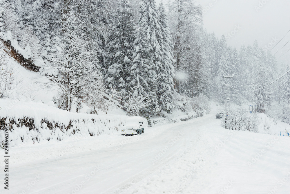 Fototapeta premium Snowy road in winter with an SUV parked.