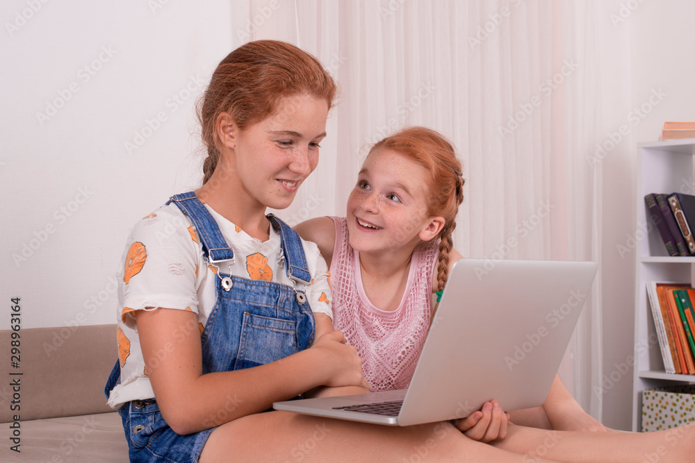 Young attractive girls teenager with red hair sits on a sofa at home with a laptop. Young attractive girls teenager with red hair sits on a sofa at home with a laptop.
