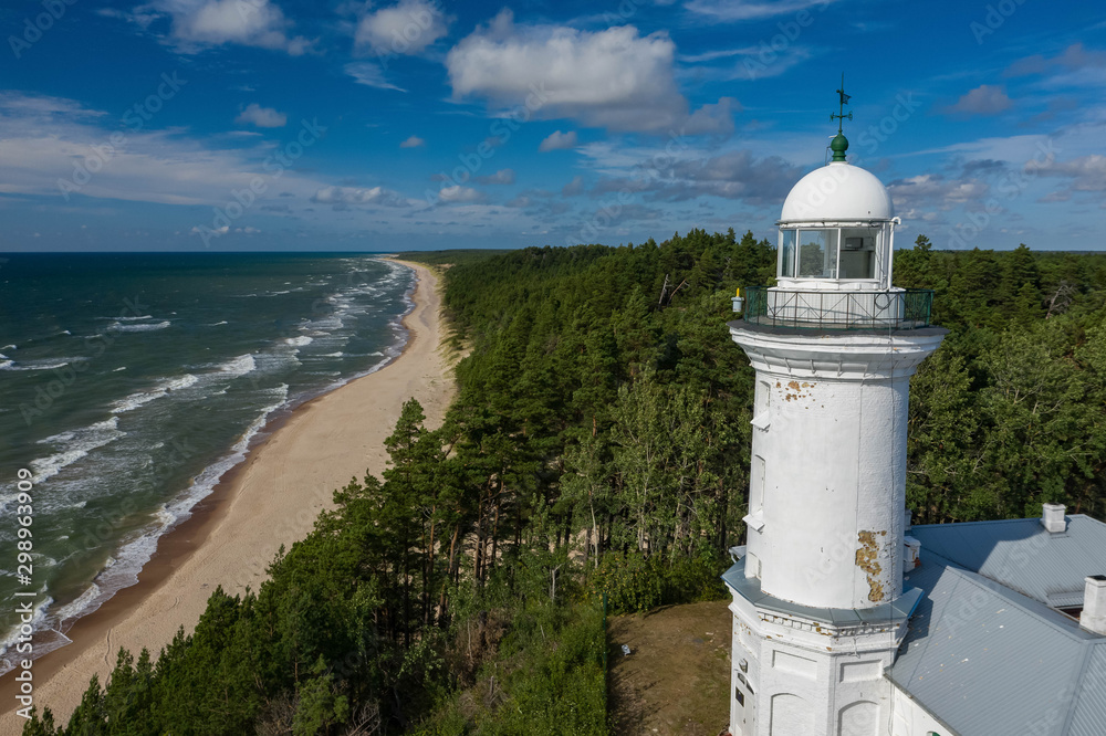 White Uzhava lighthouse on the shore of Baltic Sea. Sunny day.