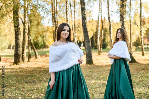Ladies in elegant green dresses walking in autumn park. Brunette girl Dreamy young girls laughing on the outdoors
