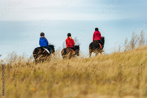 Family Horseback riding during autumn day with tall grass foreground