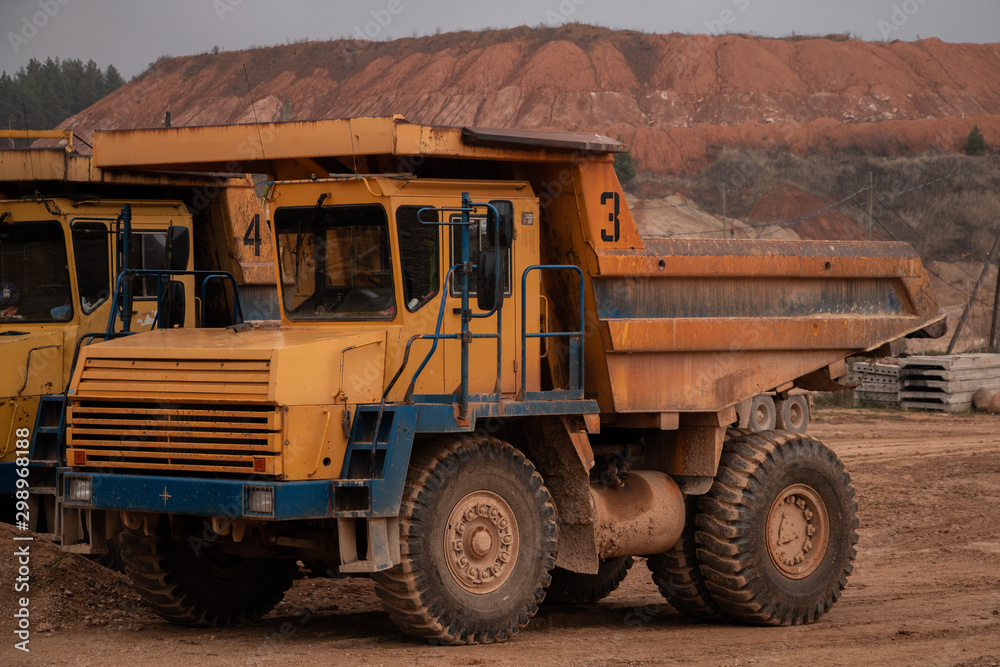 Huge old quarry yellow truck on a quarry background. Big heavy equipment for work in quarries.